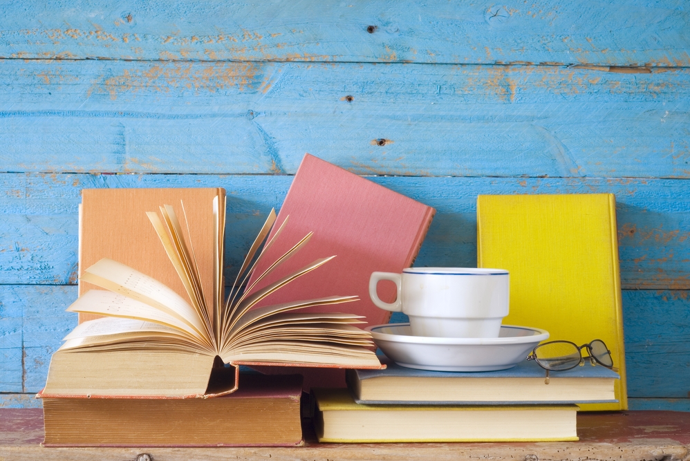 pile of books, tea and a pair of glasses with blue background